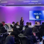 جلسة في معسكر الذكاء الاصطناعي بغرفة المدينة المنورة، مع متحدثة وحضور وشاشة MedAI