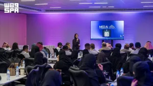 جلسة في معسكر الذكاء الاصطناعي بغرفة المدينة المنورة، مع متحدثة وحضور وشاشة MedAI