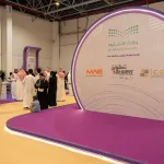 زوار داخل معرض التعليم والتدريب بجدة بجوار جناح يحمل شعار الإدارة العامة للتعليم بالمحافظة